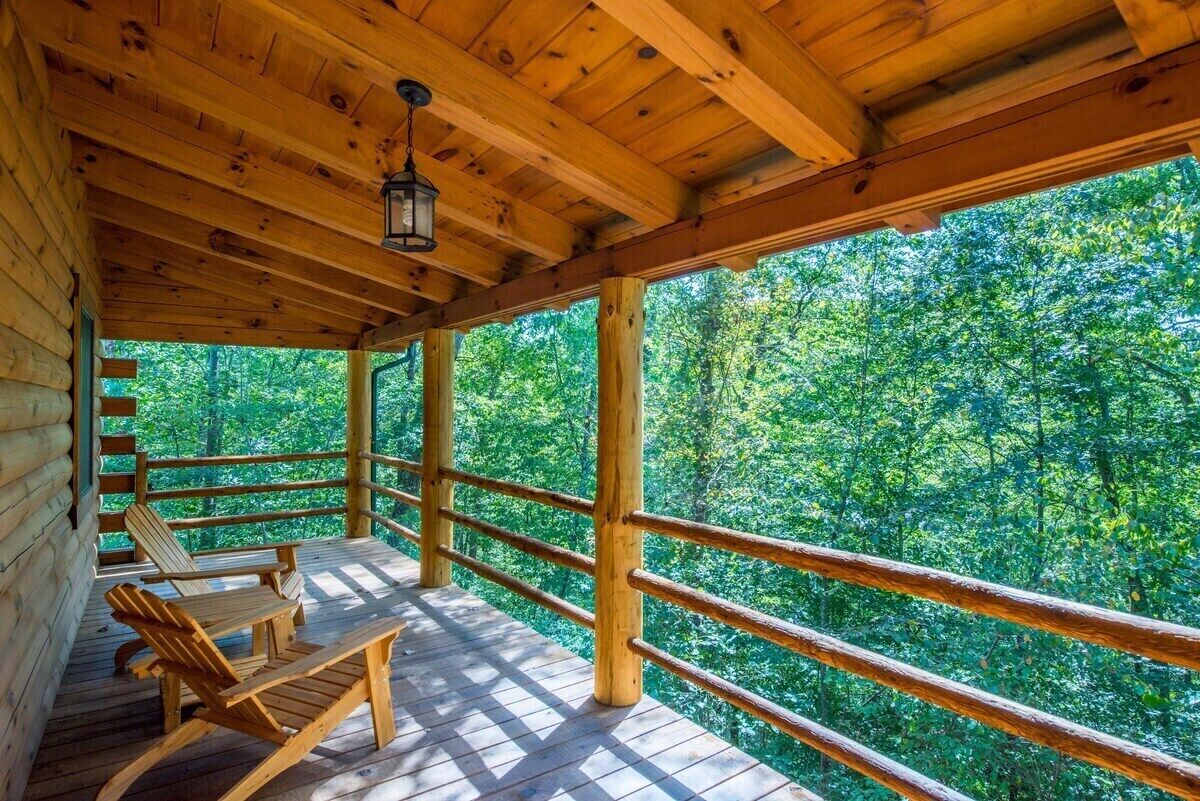 A wooden deck with a railing, wooden chairs, and a hanging lantern.