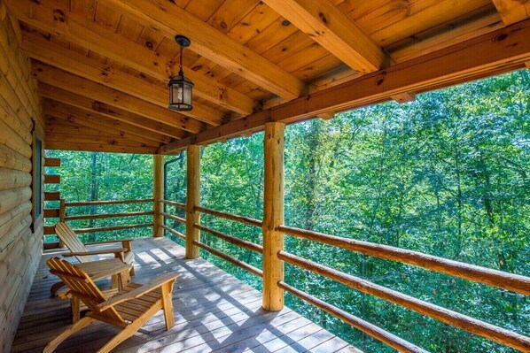 A wooden deck with a railing, wooden chairs, and a hanging lantern.