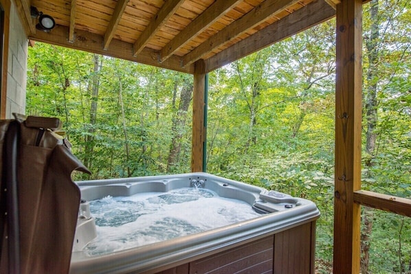 Ein Whirlpool in einer Holzblockhütte mit Blick auf den Wald.
