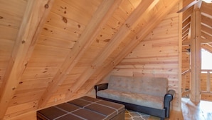 Une pièce mansardée chaleureuse avec des murs en bois et un canapé.