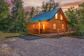 A log cabin with a porch and a metal roof, surrounded by trees. - Buck Ridge Cabin | Hocking Hills, 12 Acres, Pets (Rockbridge)
