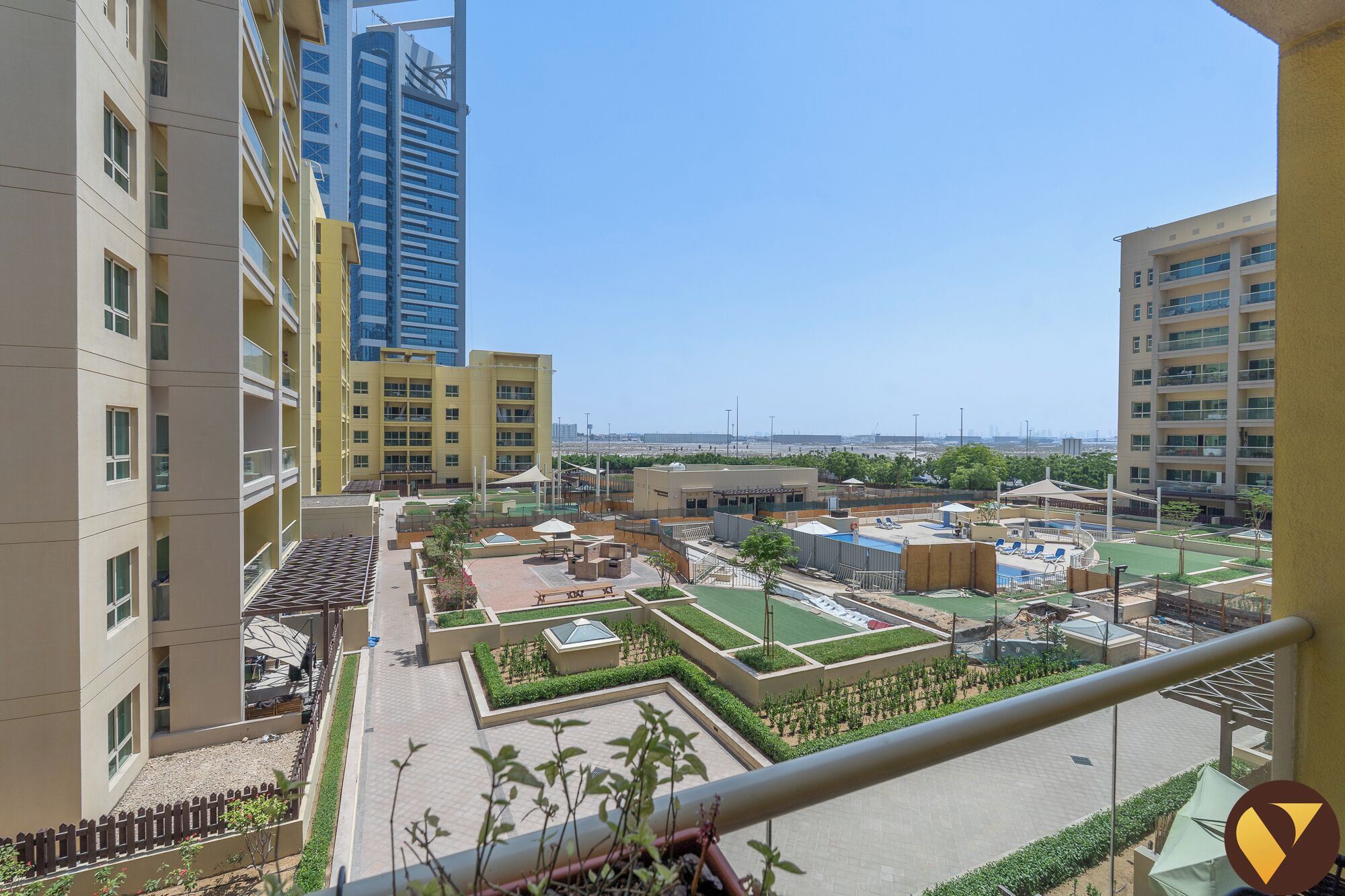 A residential area with modern buildings, a swimming pool, and a landscaped garden.