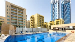 Una piscina interior con sillones de descanso, un flotador salvavidas y edificios altos al fondo.