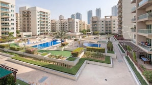 Un complejo residencial con varios edificios de gran altura, piscina y jardines ajardinados.