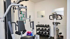 A gym with exercise equipment, dumbbells, and a mirror.