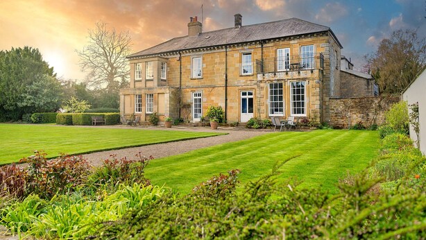 A large stone building with multiple windows and a well-maintained lawn.