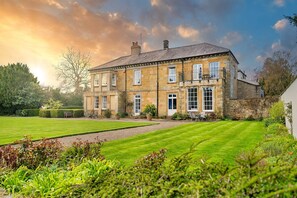 A large stone building with multiple windows and a well-maintained lawn.
