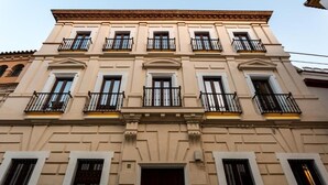 A multi-story building with a symmetrical facade, evenly spaced windows, and balconies with black railings.