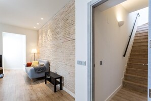 Una sala de estar moderna con pared de ladrillo, un sofá, una mesita y una escalera con escalones de madera.