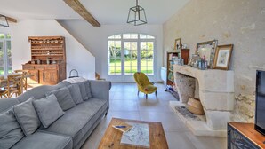 A spacious living room with a grey sofa, wooden cabinet, and a fireplace. - Domaine des Cyclamens (Verneuil-sur-Indre)