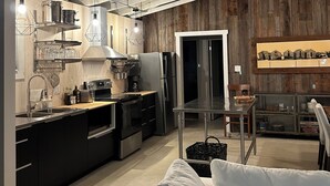 Eine moderne Küche mit Edelstahlgeräten, einer Holzwand und einem Essbereich mit einem weißen Sofa.