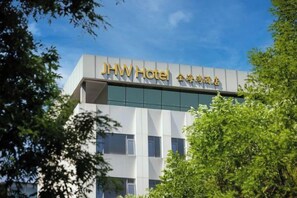 Ένα σύγχρονο κτιριακό συγκρότημα ξενοδοχείου με μια ευδιάκριτη πινακίδα που αναγράφει «Ξενοδοχείο JHW».