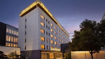 Ein modernes Hotel mit einem markanten Eingang, mehreren Etagen und einer gut beleuchteten Fassade.