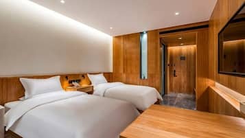 Ein Hotelzimmer mit zwei Betten, einem Holztisch, einem Spiegel und einer Holzpaneelausstattung.