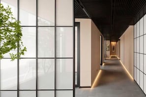 Ein Korridor mit modernem Design, links eine Wand mit Rasteroptik und eine dunkle Decke.
