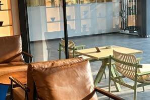 A seating area with leather chairs and a wooden table, a glass partition, and a view of the street outside. - JHW Hotel (Beijing)
