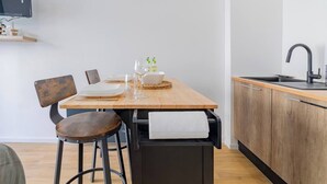 A compact kitchen with a wooden table, bar stools, a sink, and a built-in oven.