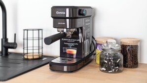 A Cumbia coffee machine with a coffee pod holder, a glass coffee pot, and two jars of coffee beans.