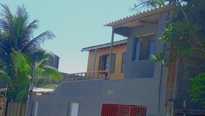 A two-story building with a balcony on the upper floor, a red gate, and a number '210' on the facade. - Cozy mini house in Arraial d'Ajuda. (Arraial d'Ajuda)