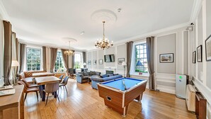 Une pièce spacieuse équipée d’une table de billard, d’un coin repas et de sièges confortables.
