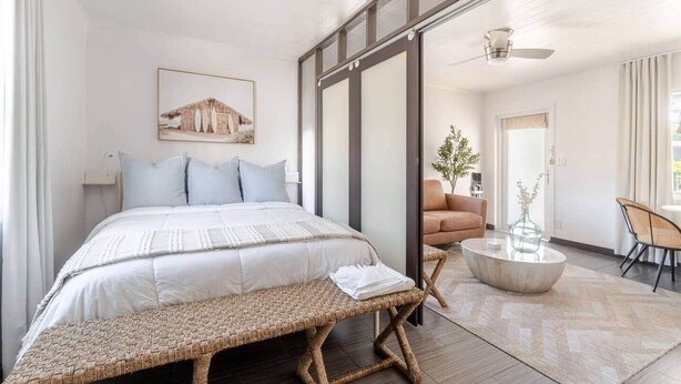 A modern bedroom with a large bed, a bench, a sofa, a coffee table, and a dining area. - "Bliss"  stylish apartment with pool, by beach (Riviera Beach)