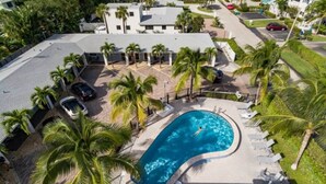 An aerial view of a residential area with a swimming pool surrounded by palm trees and a few parked cars. - "Bliss"  stylish apartment with pool, by beach (Riviera Beach)