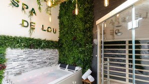 Un espace spa comprenant une grande baignoire, un mur végétal et un panneau indiquant « SPA DE LOU ».