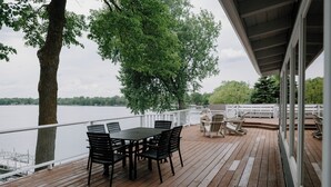 Eine Holzterrasse mit Tisch und Stühlen, die auf ein Gewässer blickt.