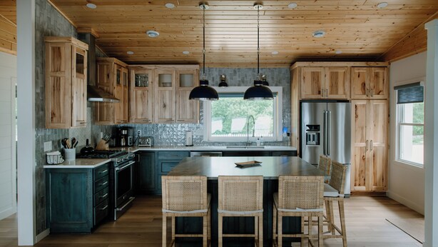Eine moderne Küche mit Holzausstattung, einer zentralen Kochinsel mit Sitzgelegenheiten und einem großen Kühlschrank.
