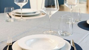 A dining table set with plates, glasses, and cutlery, with a blue upholstered chair in the background. - SCAPPO IN UMBRIA, L'attico del corso (Perugia)