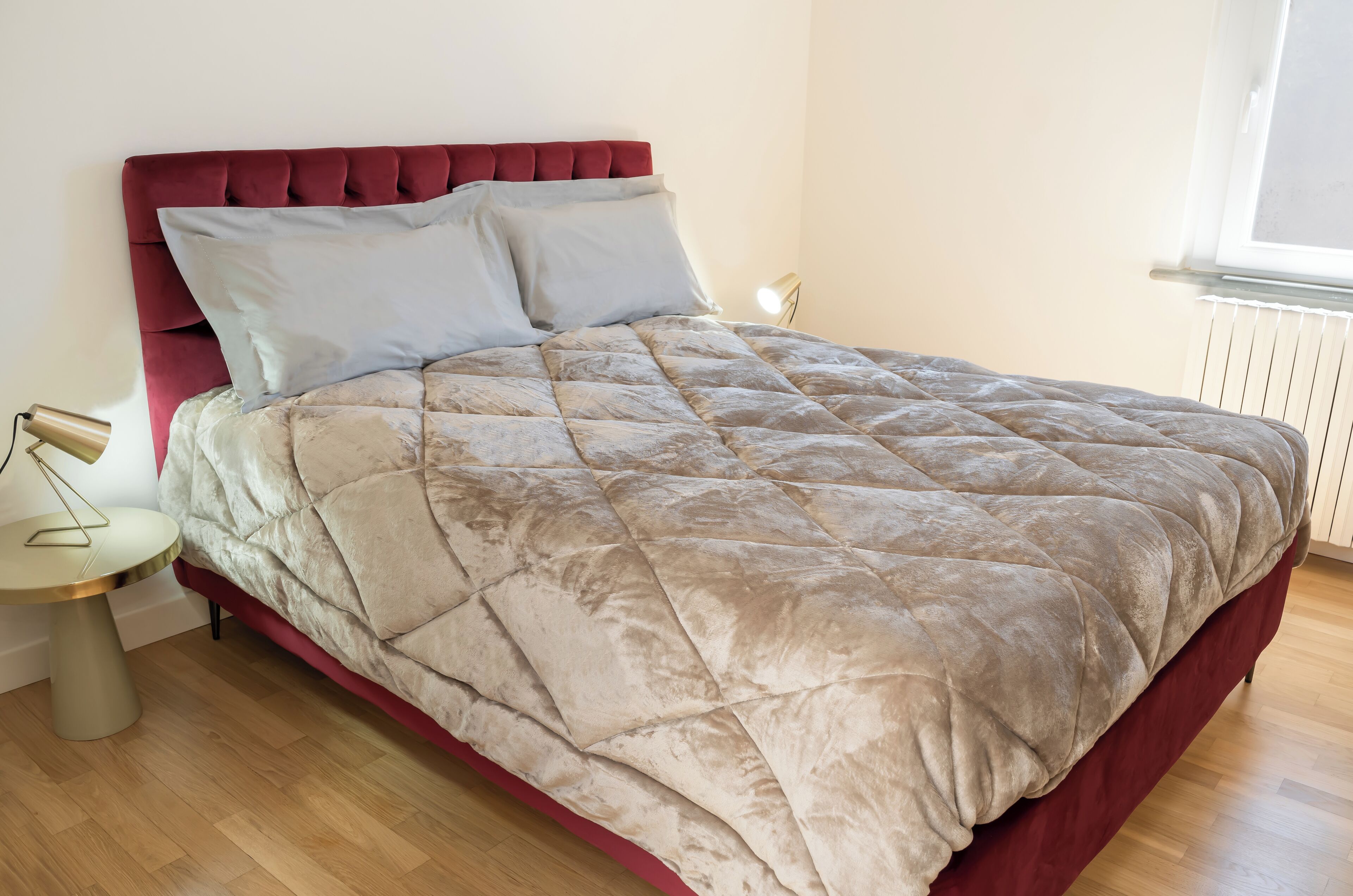 A bed with a red headboard and a beige quilted bedspread.