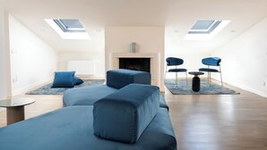 A spacious loft apartment with a high ceiling, skylights, a fireplace, a sofa set, and a dining area. - SCAPPO IN UMBRIA, L'attico del corso (Perugia)