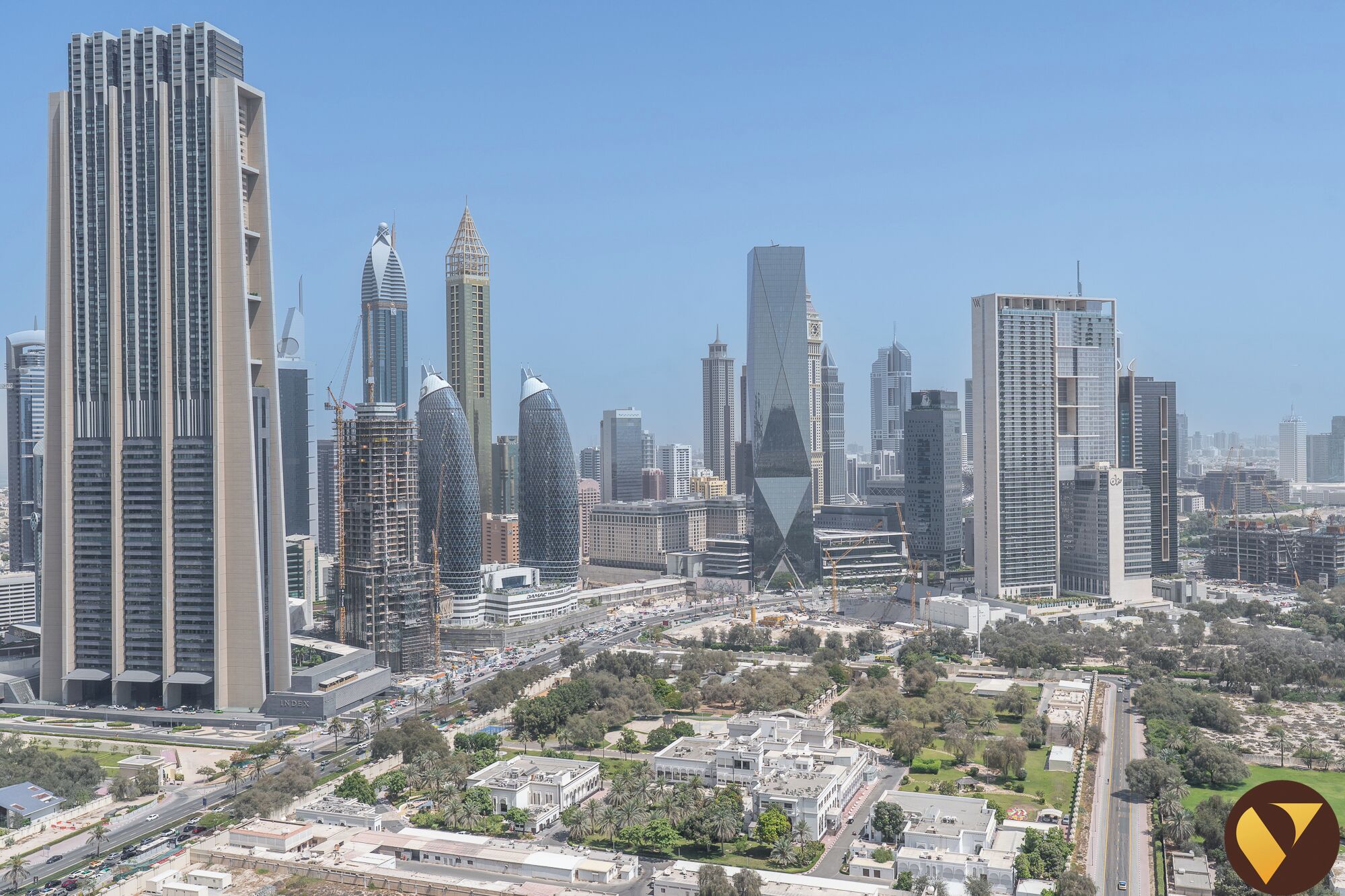 Un paysage urbain avec des immeubles modernes de grande hauteur, une place centrale et des espaces verts environnants.