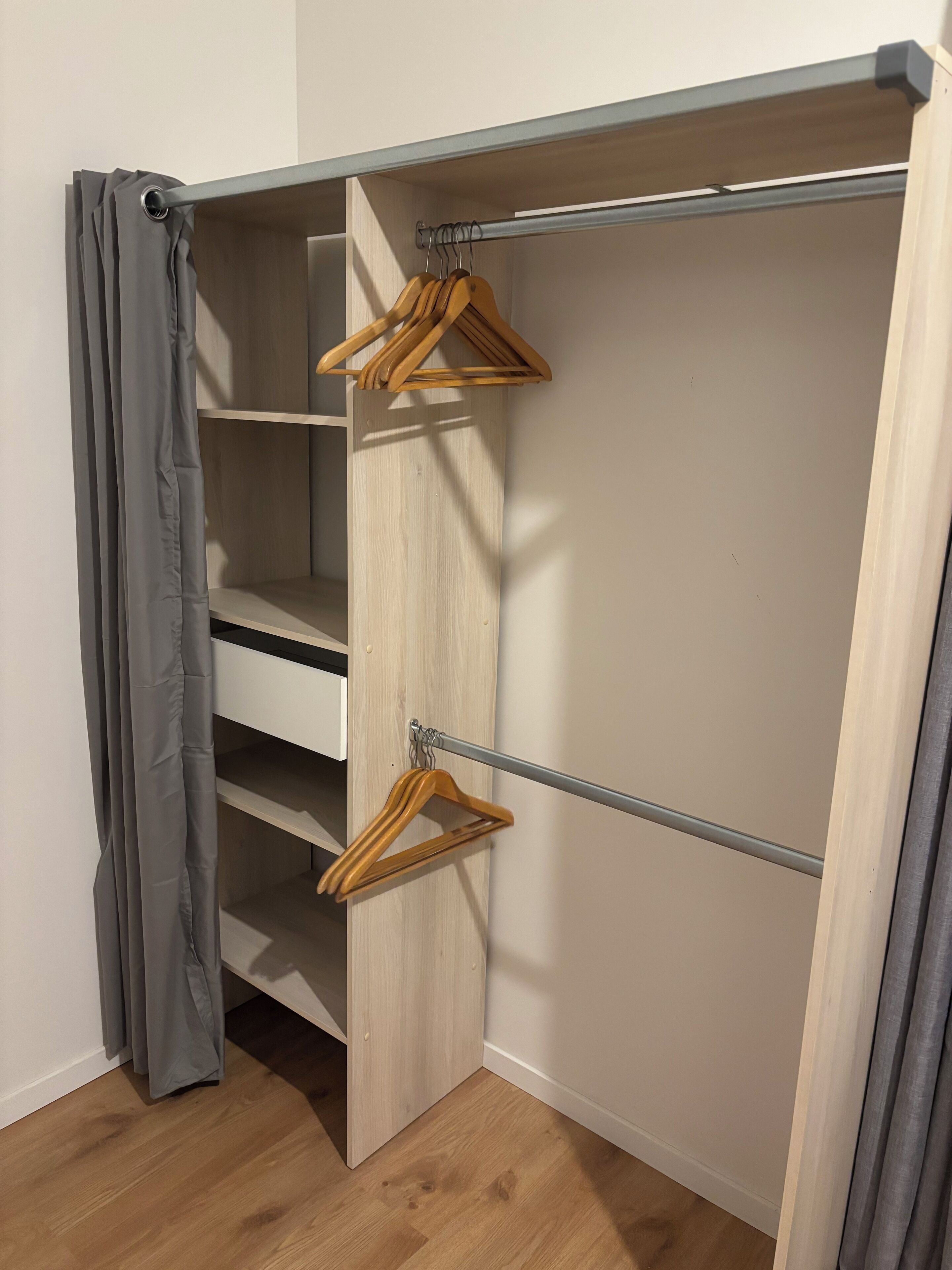 A walk-in closet with wooden shelves and a metal rod for hanging clothes.