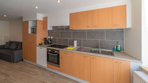 A compact kitchen with wooden cabinets, a built-in oven, and a sink. - Holiday Home in La Roche Near Center (La Roche-en-Ardenne)