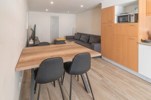 A modern kitchen with a wooden table and chairs, a grey sofa, and a microwave on the countertop. - Holiday Home in La Roche Near Center (La Roche-en-Ardenne)