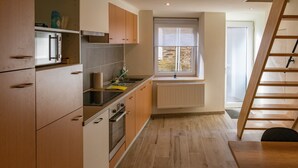 A modern kitchen with wooden cabinets, a built-in oven, and a window with a view. - Holiday Home in La Roche Near Center (La Roche-en-Ardenne)