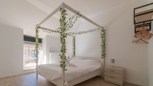 A bedroom with a canopy bed, wooden floor, bedside table, and a view of the outside. - Holiday Home in La Roche Near Center (La Roche-en-Ardenne)