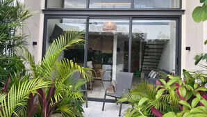 A modern building with large glass doors, a staircase, and a seating area with chairs and a table. - Modern apartment in Tulum trendy zone, pool and wifi (tulum)