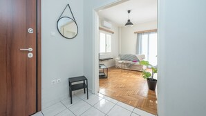 A hallway leading to a living area with a sofa, a small table, and a potted plant. - 2BD - Center of Athens - 4mins Walk To Acropolis (Athina)