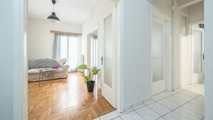 A bright, open living area with a wooden floor, a sofa, a coffee table, and a potted plant. - 2BD - Center of Athens - 4mins Walk To Acropolis (Athina)