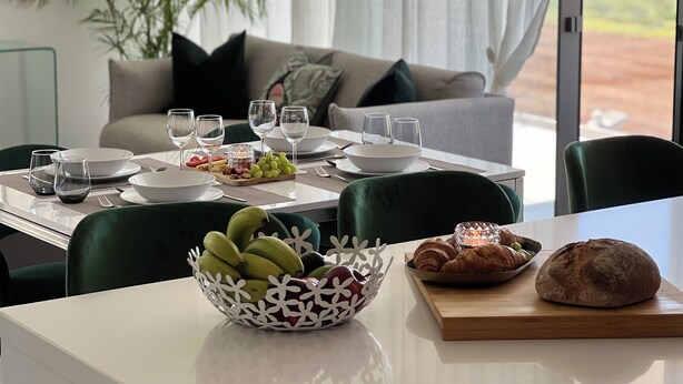 Una mesa de comedor servida con platos, vasos y un frutero.