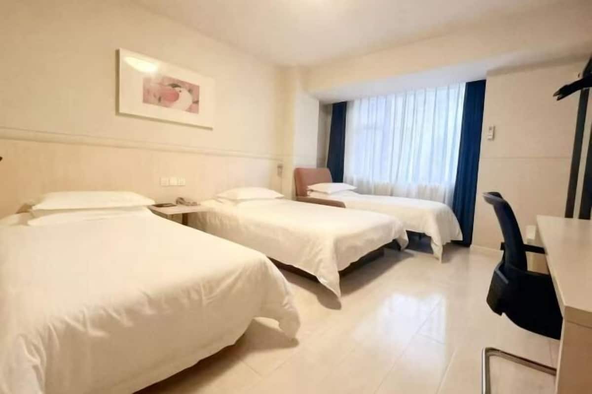 A hotel room with two beds, a desk, a chair, and a window with curtains.