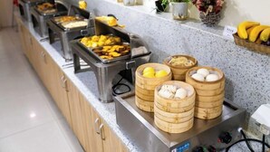 Disposição de buffet com diversos alimentos em recipientes, incluindo cestas de madeira com ovos e uma bandeja de metal com frutas fatiadas.