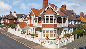 A Victorian-style house with a bay window, multiple chimneys, and a white picket fence. - Apartment in Brighton Near the Beach (Brighton)