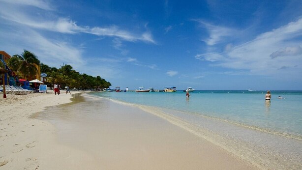 Una spiaggia con acque cristalline, ombrelloni e barche.