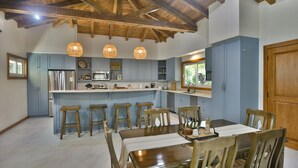 Un'ampia cucina con isola centrale, travi a vista in legno e illuminazione a sospensione.