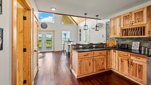 A kitchen with wooden cabinets, a black countertop, and a skylight. - Tennessee Whiskey Cabin- Lake and Mtn Views, Covered Deck, Game Room, Pool Table, BBQ, Pets (Sevierville)
