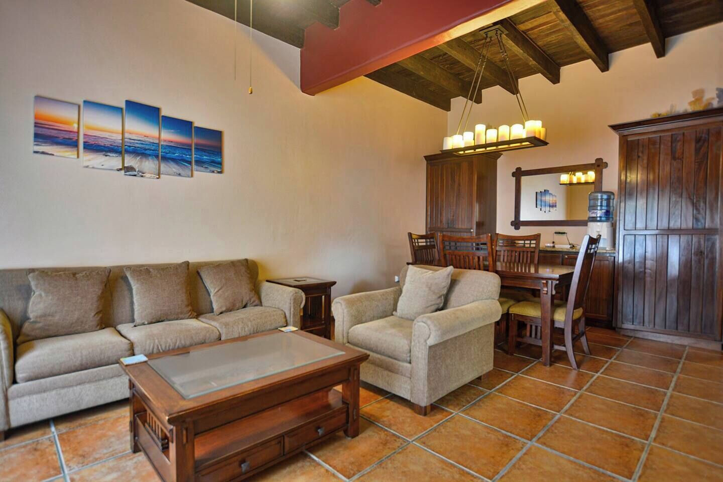 A living room with a sofa, armchair, coffee table, and dining area with chairs and a table.