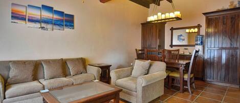A living room with a sofa, armchair, coffee table, and dining area with chairs and a table.